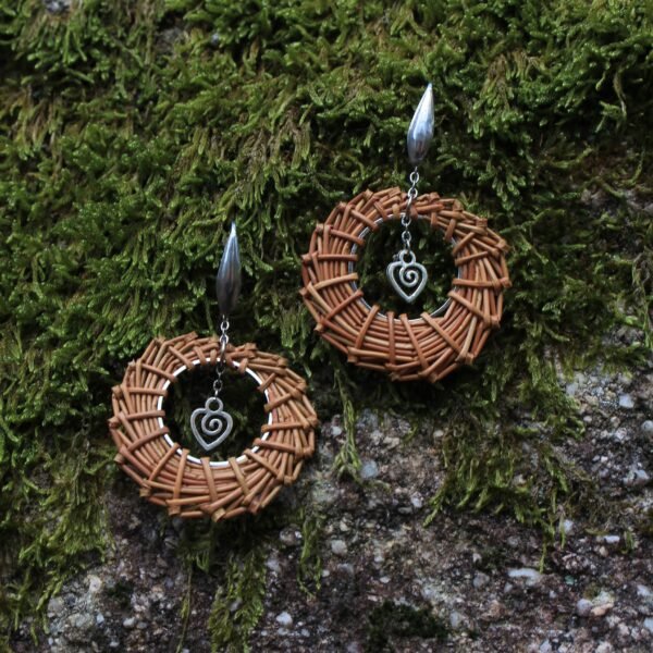 Boucles d’oreilles cœur en acier inoxydable argenté et aiguilles de pin laricio tressées à la main, vue de face.